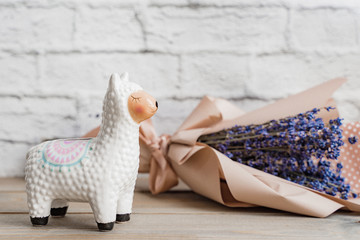 Fototapeta na wymiar Llama money box on the table with bouquete of gried lavanter on white background