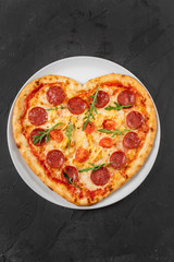 Heart shaped pizza with meat and vegetables. Food concept of romantic love for Valentines Day.