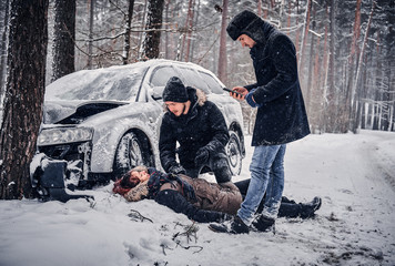 Witness of the accident helps the injured couple to contact the rescue service. The car got into a skid and crashed into a tree on a snowy road. 