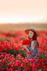 young girl in field of poppies in the bright hat