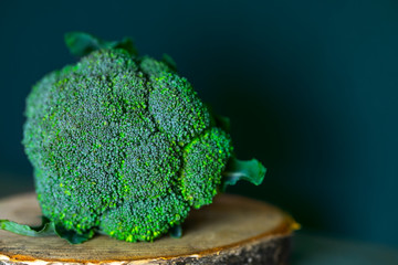 Fresh broccoli on a wooden stand on a green background. The concept of healthy eating.