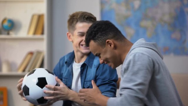 Emotional multiracial teenage friends cheering for national soccer team, fans