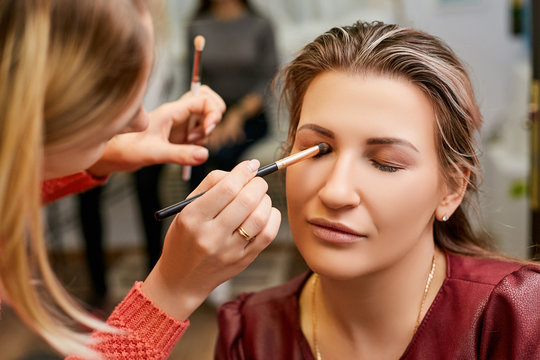 Makeup artist applies makeup to the eyelids of a woman. Client in a beauty salon.