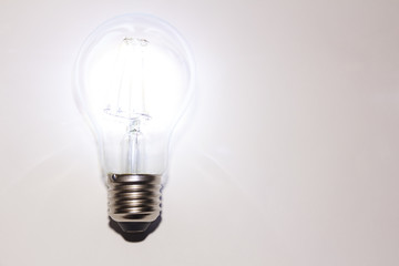 Luminous decorative LED light bulb of an isolated white surface with copy space under the text.