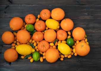 Citrus mixed oranges, tangerines, lemons and lime lie on a black wooden background from boards.