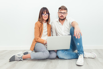 Two young coworkers dressed casual using laptop in white interior