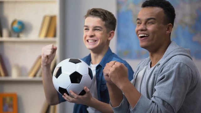 Multiracial young friends cheering, favorite football team scoring goal, leisure