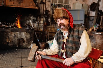 portrait of a blacksmith with a beautiful thick mustache with a huge hammer in the hands on the...