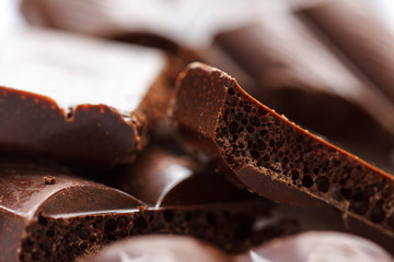 Chocolate broken into pieces. Pieces of tasty dark chocolate on white background