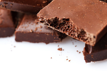 Chocolate broken into pieces. Pieces of tasty dark chocolate on white background