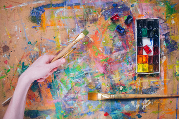 Woman hand  holding a brush and painting colorfull abstract oil picture.