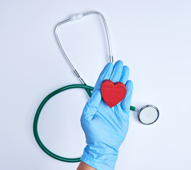human hand with blue sterile gloves holding a red heart