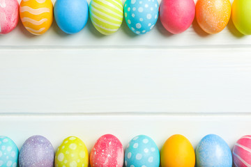 Decorative Easter eggs on white wooden background, space for text. Top view