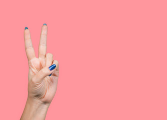 Closeup view of beautiful female hands making v gesture isolated on pink background. Horizontal...