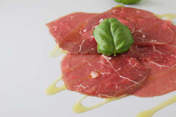 beef carpaccio on a light gray basil background