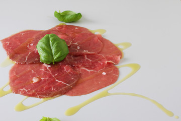 beef carpaccio on a light gray basil background