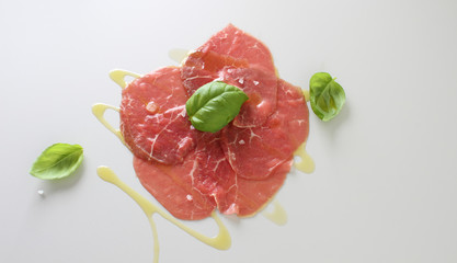 beef carpaccio on a light gray basil background
