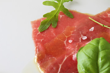 beef carpaccio on a light gray basil background