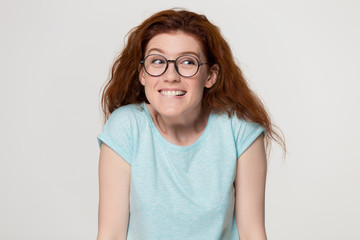 Cute shy redhead girl in glasses biting lips feeling embarrassed