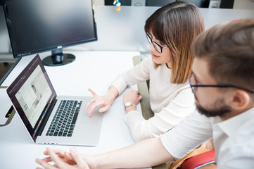 Beautiful young man and woman wearing casual working by laptop in the office