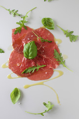 beef carpaccio on a light gray basil background