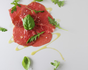 beef carpaccio on a light gray basil background