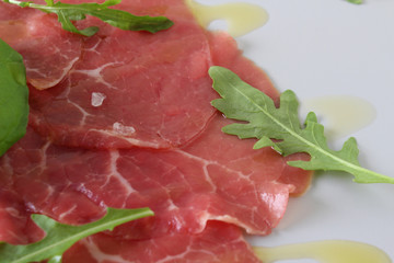 beef carpaccio on a light gray basil background