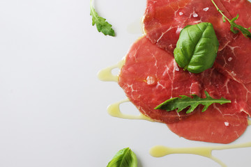 beef carpaccio on a light gray basil background