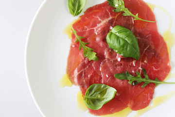 beef carpaccio on a light gray basil background