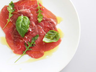 beef carpaccio on a light gray basil background