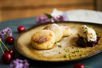 Cottage cheese pancakes, syrniki on rustic wooden table, close-up.