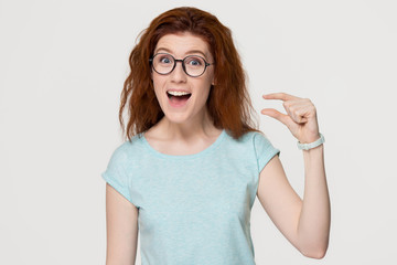 Funny excited redhead woman showing something tiny isolated on background