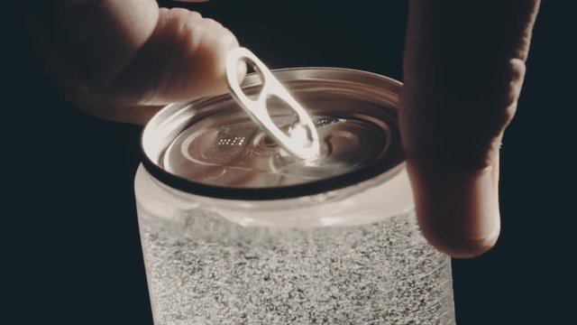 Man opens the transparent beverage can against black background