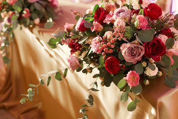 The table of the newlyweds covered with a tablecloth of gold color with a beautiful bouquet of blooming flowers