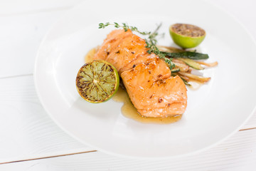 Salmon with lime and grilled vegetables witn sauce on white plate. Healthy food concept