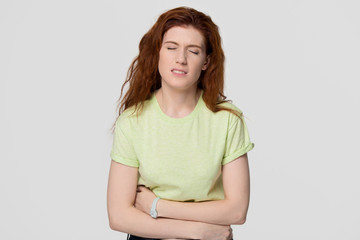Sick upset redhead woman feeling stomach ache holding belly