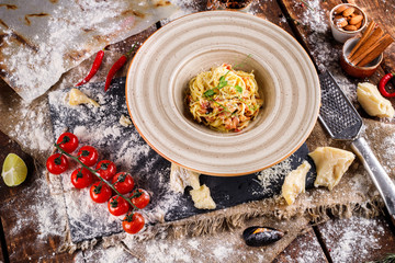 Pasta Carbonara with Parmesan on a white plate. Restaurant food at the wooden table