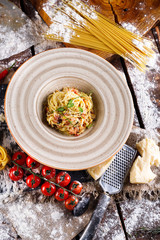 Pasta Carbonara with Parmesan cheese and sauce on a plate on a wooden background