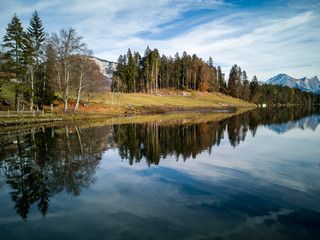 Chapfensee, Spiegelnder Stausee in der Schweiz, bei schönem Wetter mit Tannen und Bergen im Hintergrund