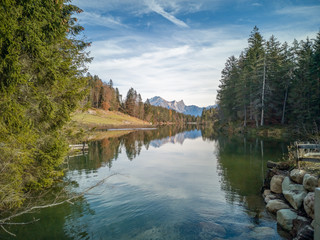 Chapfensee, Spiegelnder Stausee in der Schweiz, bei schönem Wetter mit Tannen und Bergen im Hintergrund