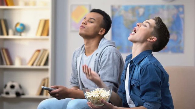 Teenagers watching show in TV and throwing popcorn in mouth, procrastination