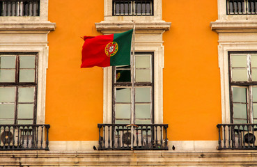 Fototapeta na wymiar Flagge von Portugal vor einer traditionellen, gelben Hauswand