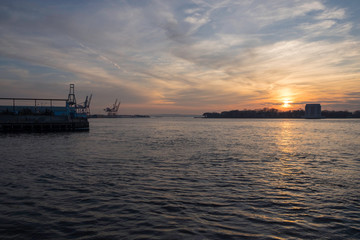 sunset over island in river with industrial machines