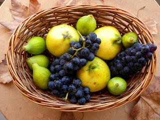bunch of grapes, figs and quince in a basket