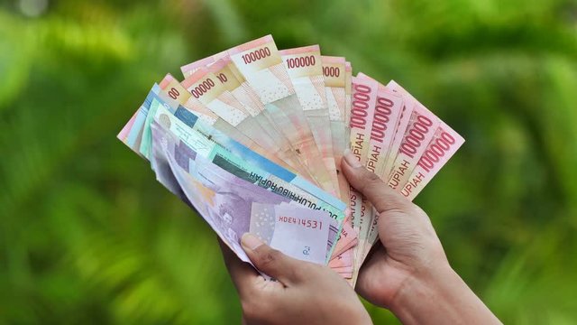 The girl is holding Indonesian money. Indonesian rupee.