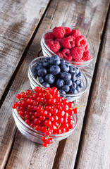Berries fresh vibrant color close up arrangement in glass jars slanted on wooden table in studio