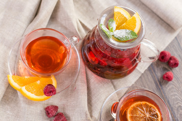 Colorful hot citrus vitamin tea in glass spot and cups