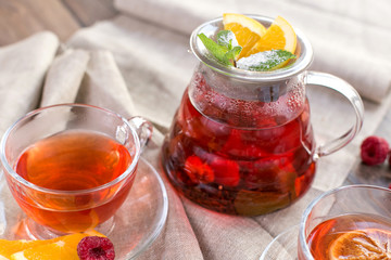 Colorful hot citrus vitamin tea in glass spot and cups