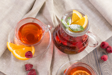 Colorful hot citrus vitamin tea in glass spot and cups