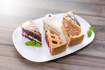 Cakes with caramel, chocolate, jam, cheese, nuts on plate